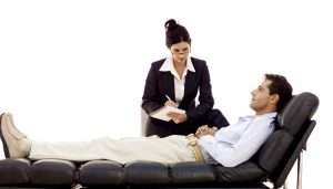 Businesswoman consulting with reclining businessman.