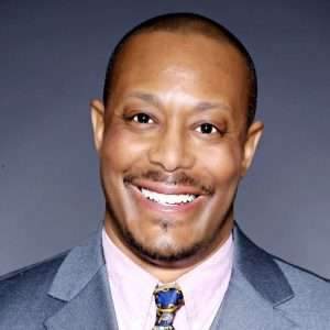 Smiling man in suit with grey background.
