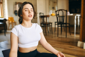 Woman practicing relaxation with deep breathing indoors.