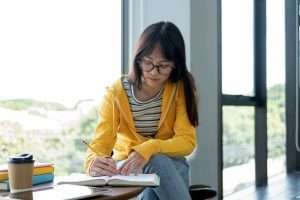 Woman studying with books in bright room.