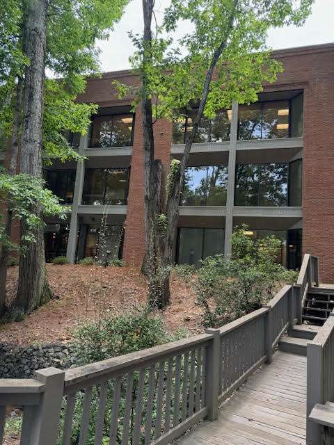 Office building surrounded by trees and wooden walkway.