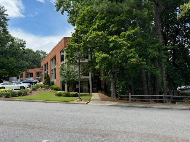 Brick office building with green trees on sunny day.