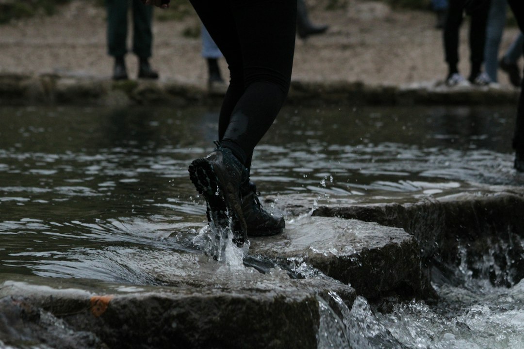 Person stepping across a stream representing movement, transition, and forward momentum