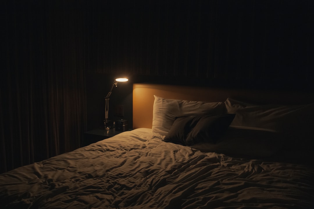 Warm bedside lamp and bed representing a calm evening sleep environment