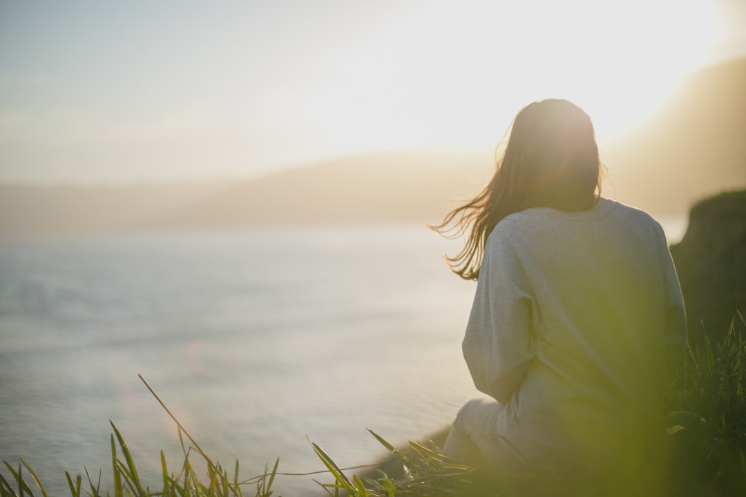 Person quietly looking toward the water representing reflection and creating space before reacting