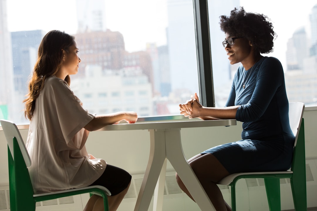 Two women talking at a table, representing communication and support.